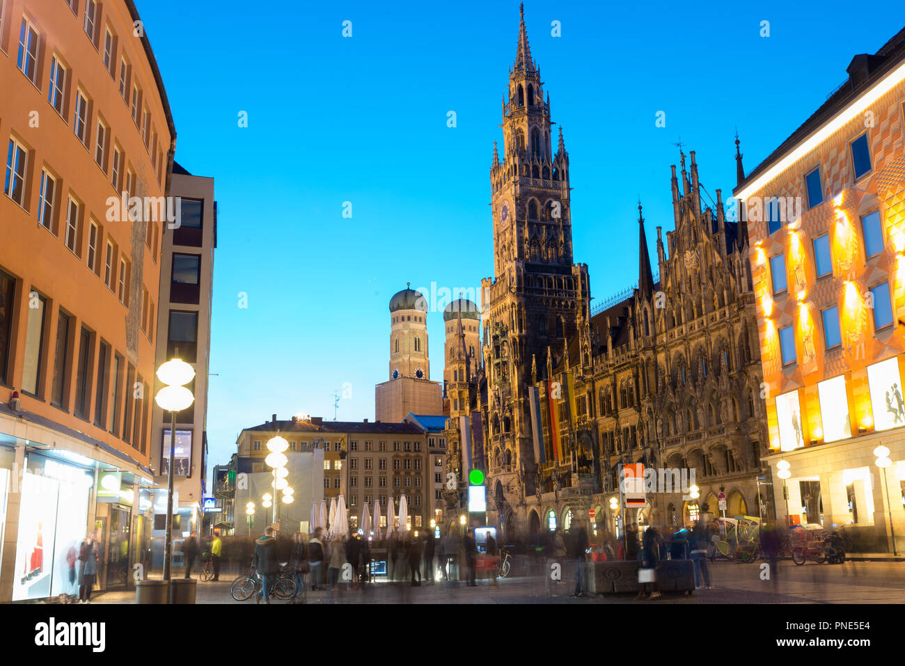 La gente a piedi la piazza Marienplatz e Munich city hall di notte a Monaco di Baviera, Germania. Caffetterie, bar, negozi e ristoranti. Il movimento di persone sfocate. Foto Stock