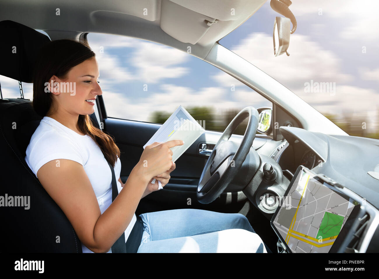 Giovane donna Guardando Diario seduti in auto la guida auto moderna Foto  stock - Alamy