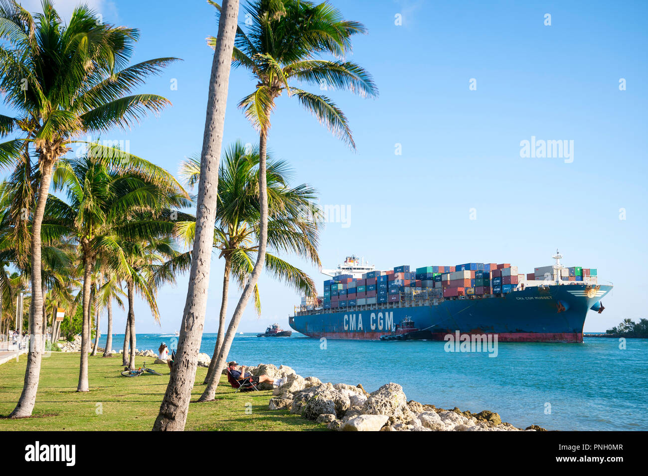 MIAMI, Stati Uniti d'America - circa agosto, 2018: trasporto container nave 'CMA CGM MUSSET' entrando in porto attraverso una stretta, palme e canale in corrispondenza della punta di South Beach Foto Stock