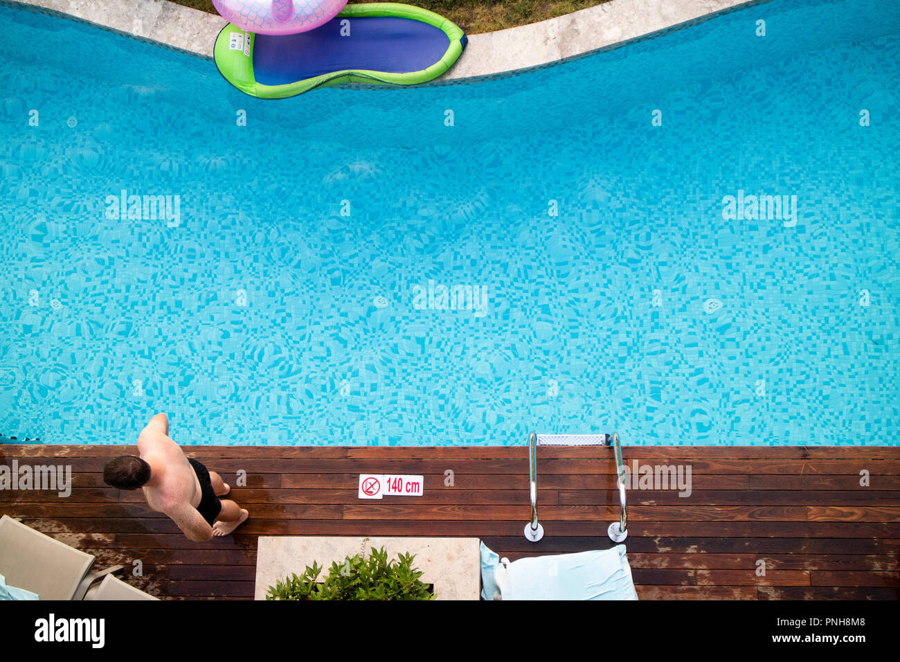 Foto aerea dell'uomo in vacanza in piedi accanto alla piscina Foto Stock