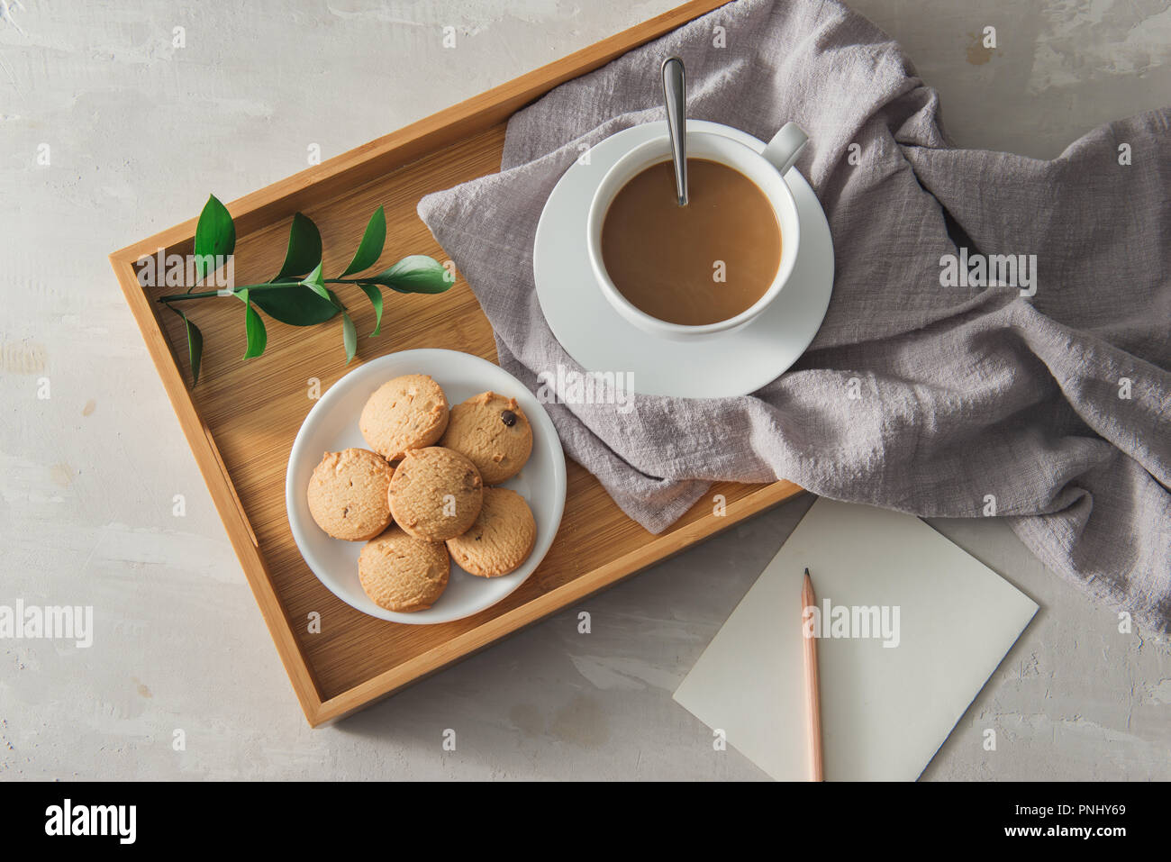 Tè con biscotti nella tazza bianca piastra con carta e matita Foto Stock