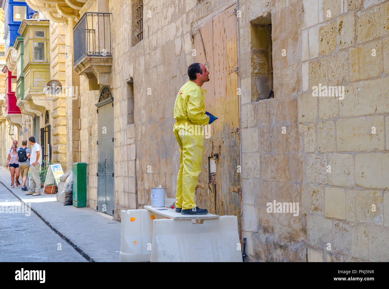 Workman utilizzando paint stripper indossando tute da lavoro ma senza una protezione per gli occhi. Foto Stock