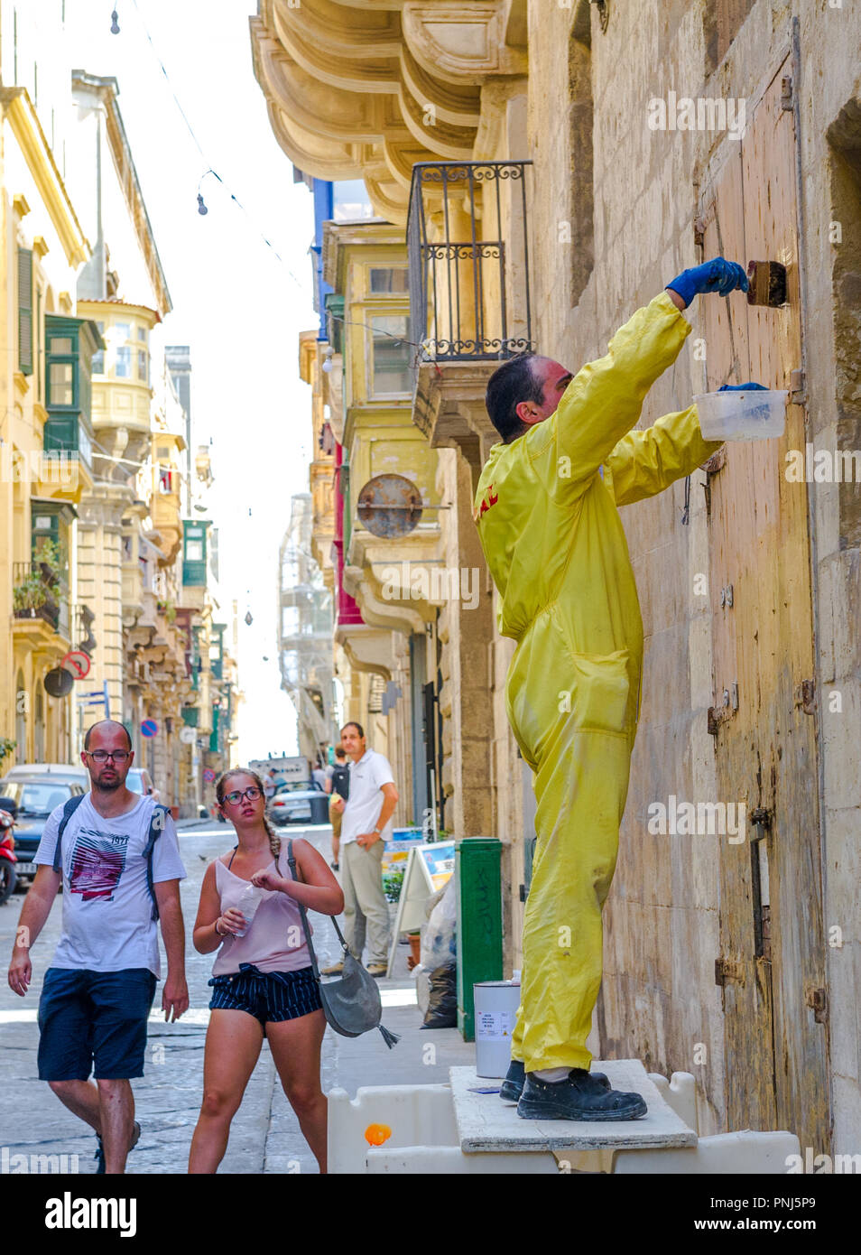 Workman utilizzando paint stripper indossando tute da lavoro ma senza una protezione per gli occhi. Foto Stock