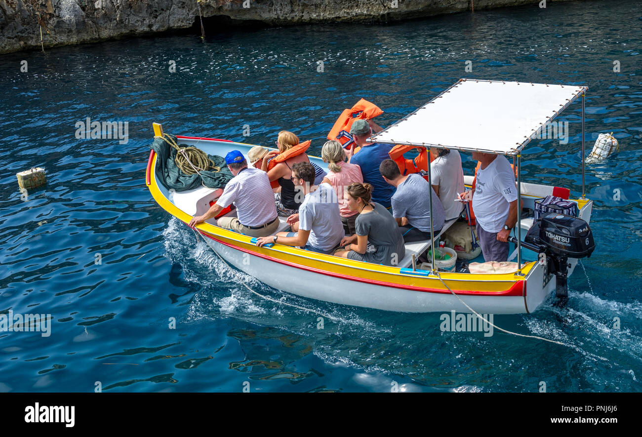 I turisti prendendo un viaggio per la Grotta Blu in piccole barche su Malta. Foto Stock