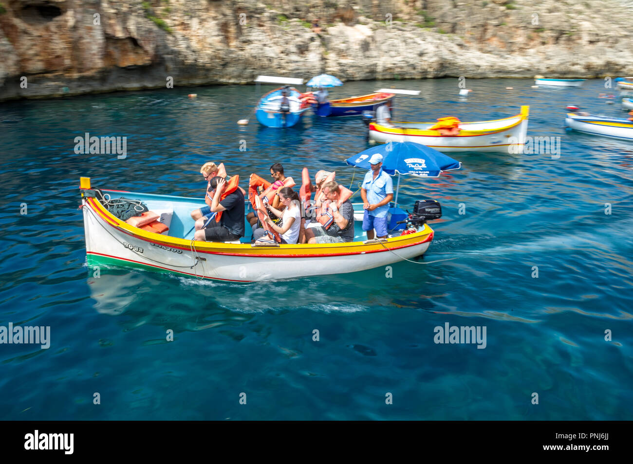 I turisti prendendo un viaggio per la Grotta Blu in piccole barche su Malta. Foto Stock