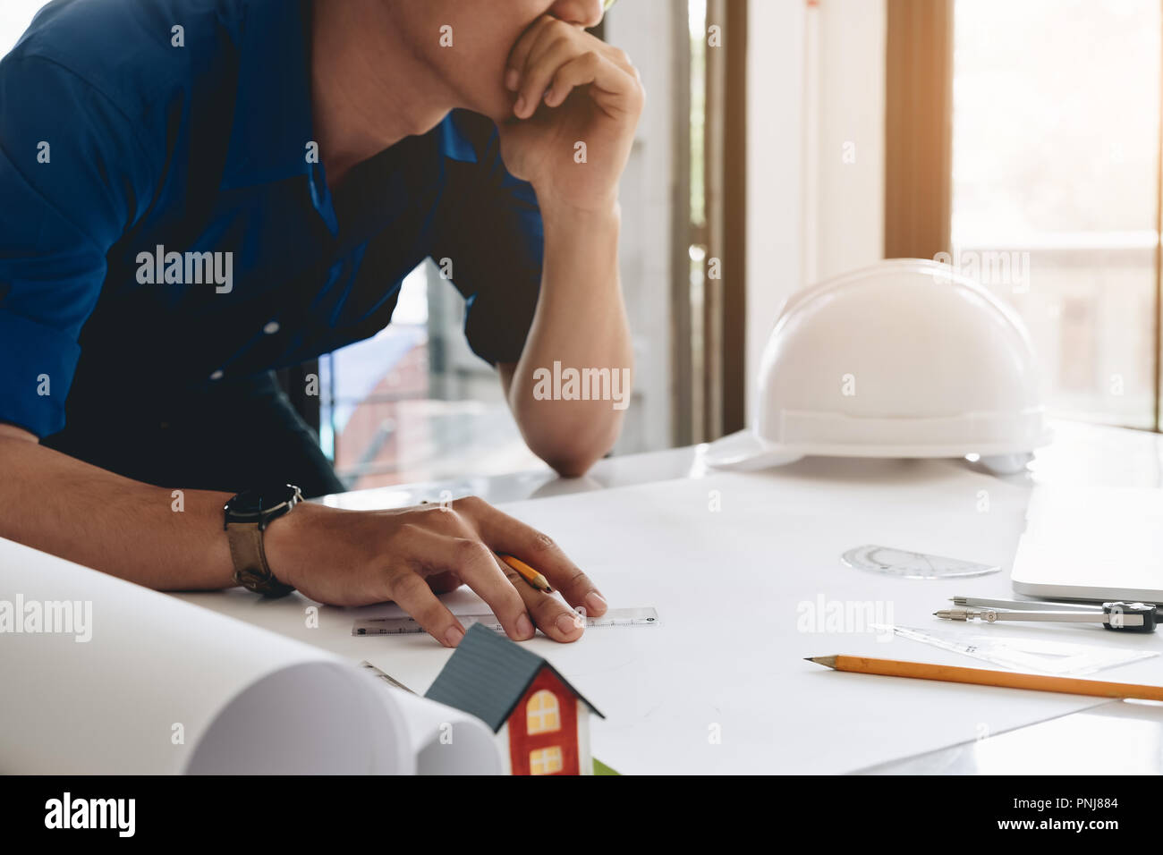 Giovane uomo che lavora per il suo progetto di piano presso il sito i lavori di costruzione. Foto Stock