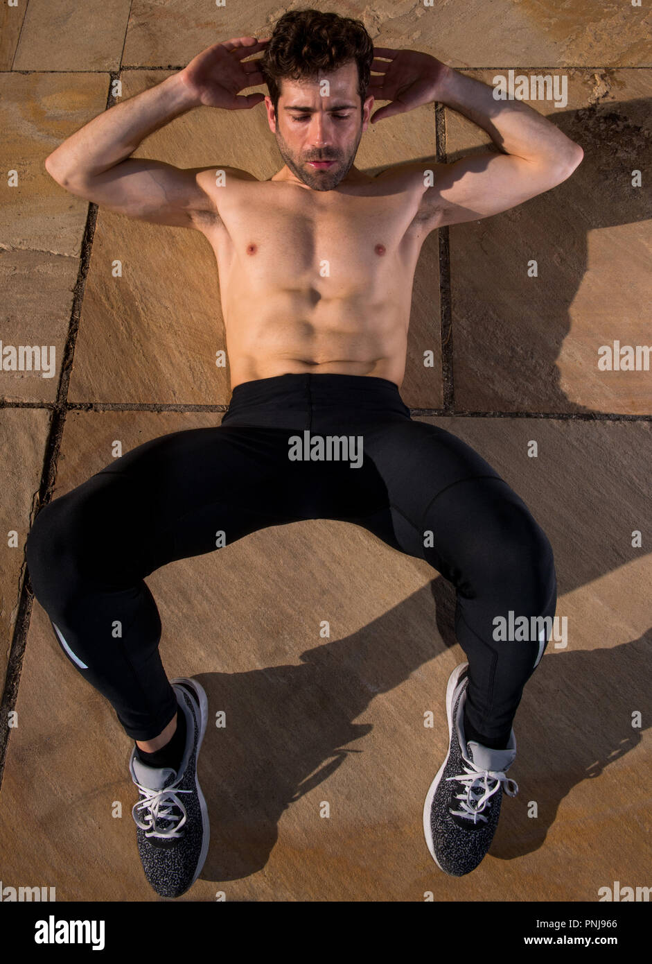 L'uomo senza t-shirt addominale rende nel terreno Foto Stock