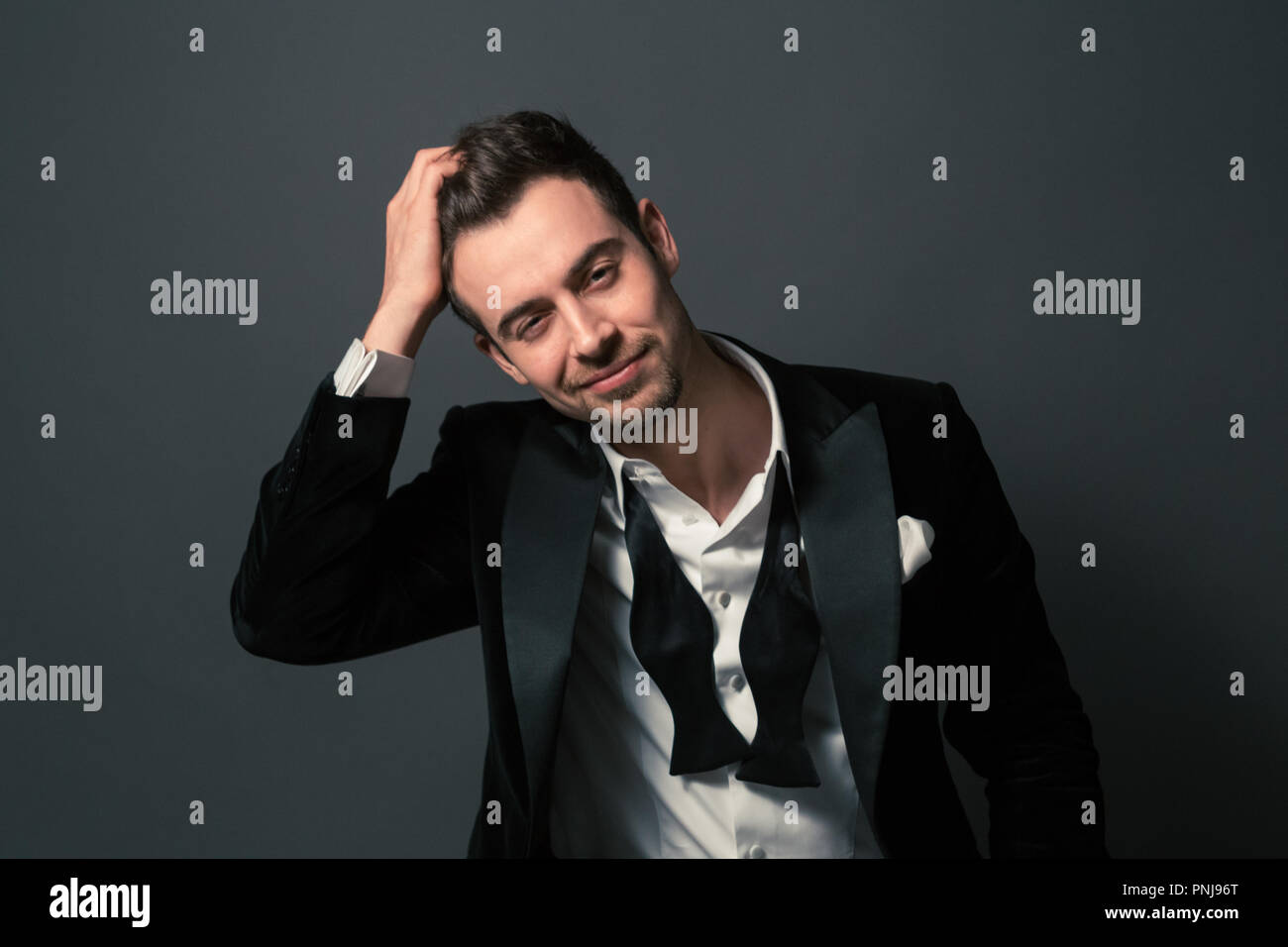 Bianco e nero ritratto di una giovane uomo bello in un vestito, sorridente e guardando la telecamera, il filtro bow tie e pulsanti shirt annullata Foto Stock