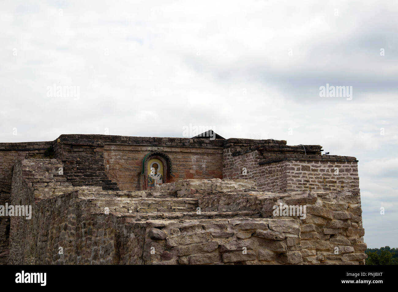 La rovina di antica fortezza parete in Izborsk, Russia, con ortodossi ikon di Nicolas il lavoratore di meraviglia Foto Stock