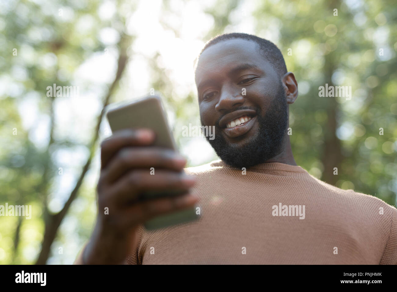 Positivo uomo gioioso usando il suo smartphone moderno Foto Stock