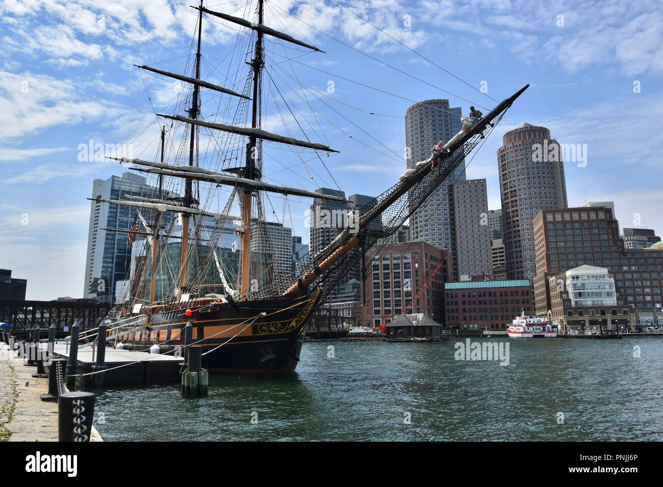 Una nave a vela nel porto di Boston contro lo skyline del centro cittadino come si vede dal South Boston Seaport, Boston, MA, Stati Uniti d'America Foto Stock