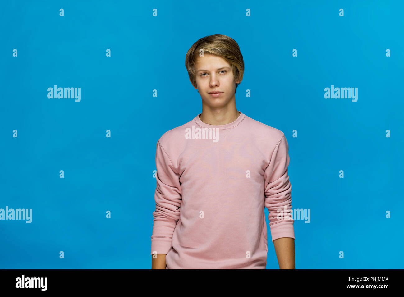 Allegro sorridente adolescente in rosa camicetta contro sfondo blu studio shot, isolato Foto Stock