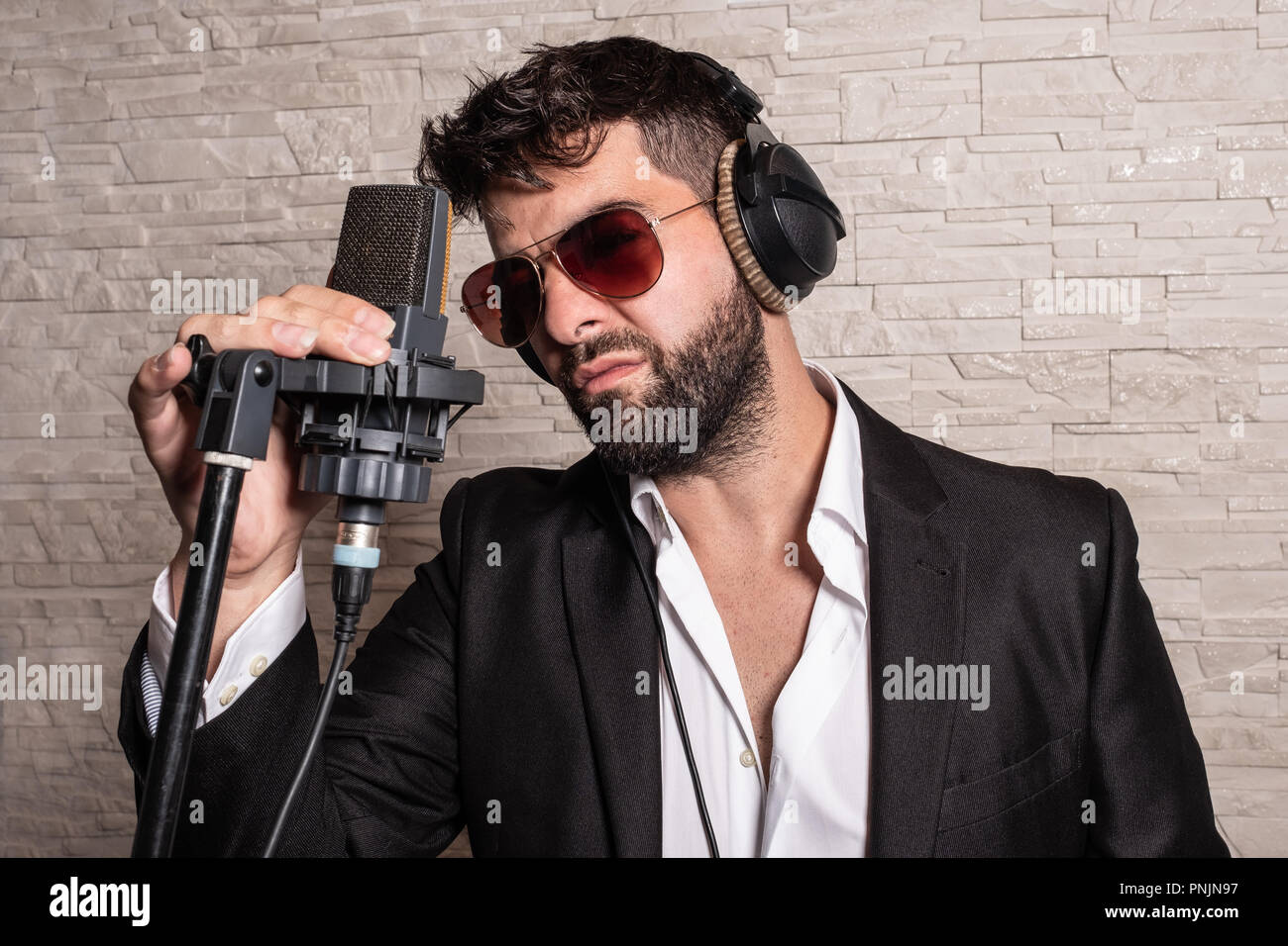 Cantante con occhiali da sole di fronte a un microfono tenendo a lui con la  mano e con alcuni caschi Foto stock - Alamy