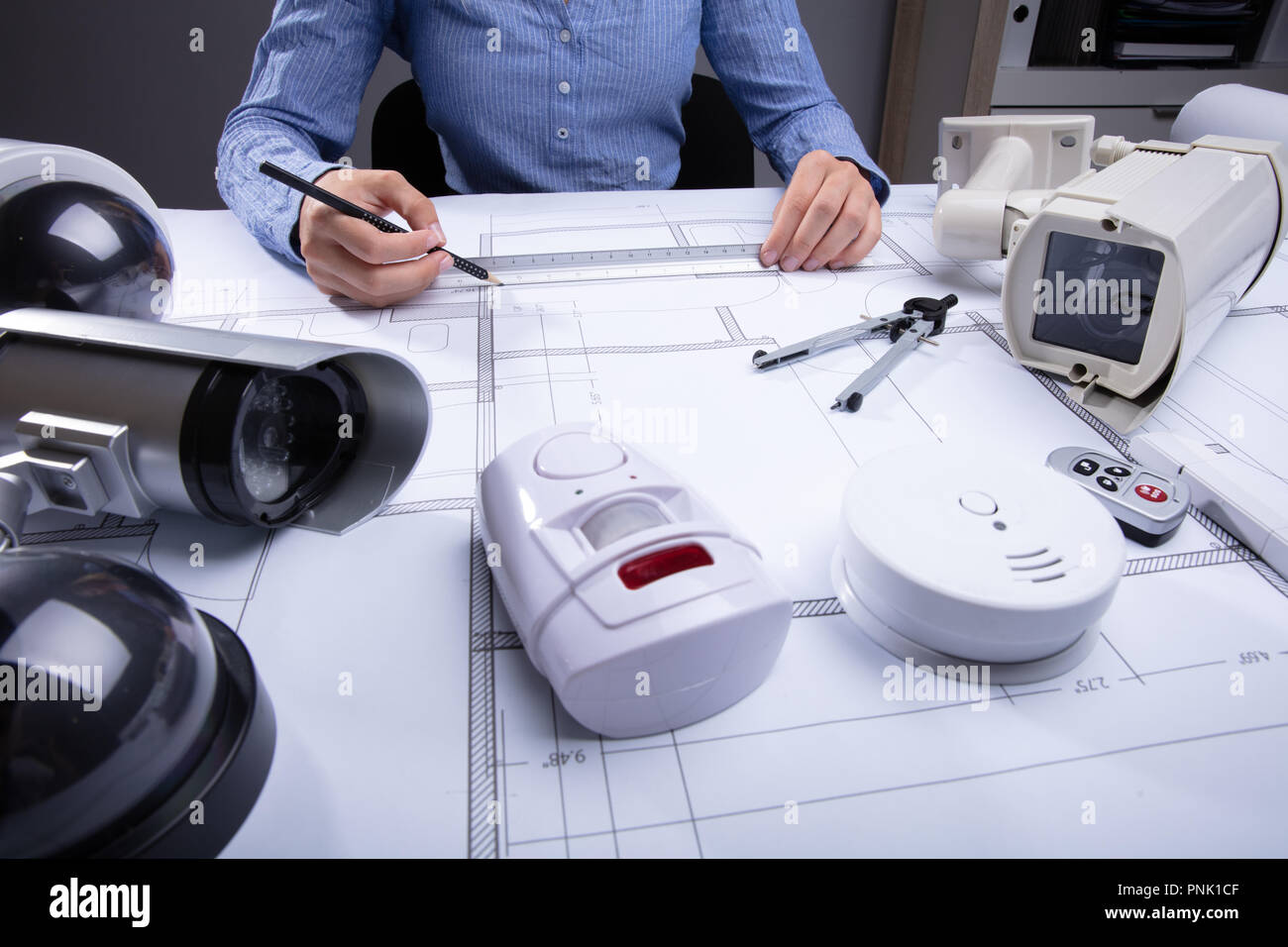Architetto disegno Blueprint con varie apparecchiature di sicurezza sulla scrivania Foto Stock