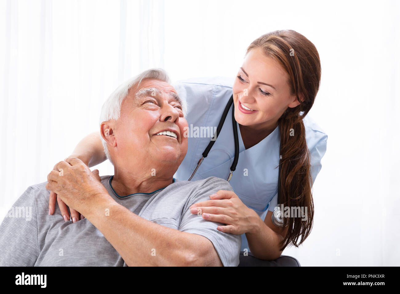 Ritratto di una donna felice infermiera Guardando uomo Senior Foto Stock