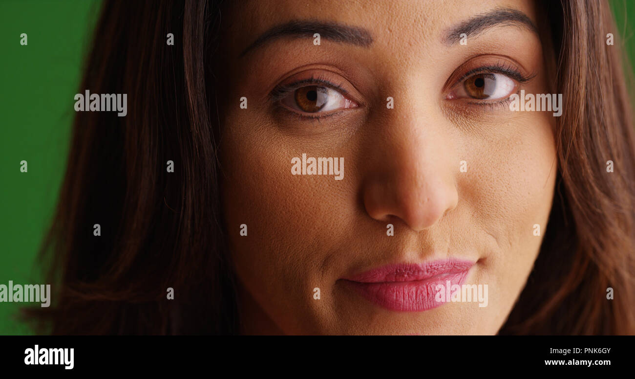 Extreme close up di bella femmina Latina guardando la fotocamera su schermo verde Foto Stock