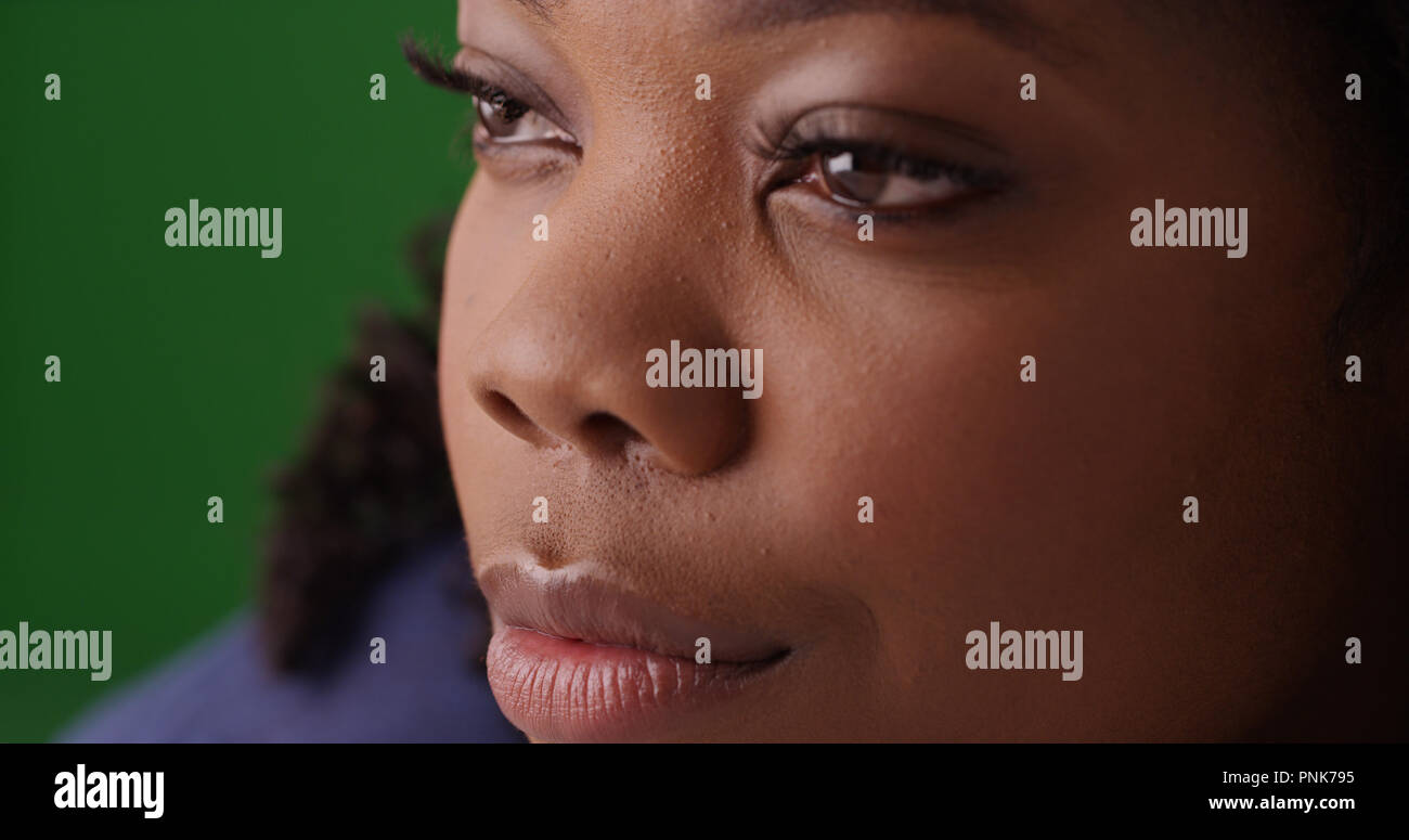 Close up nero adorabile volto di donna come lei si guarda al di fuori dello schermo su schermo verde Foto Stock