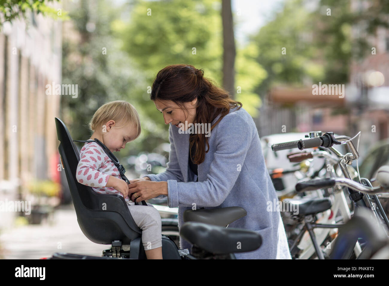 Madre di mettere il bambino in sella per bicicletta Foto Stock