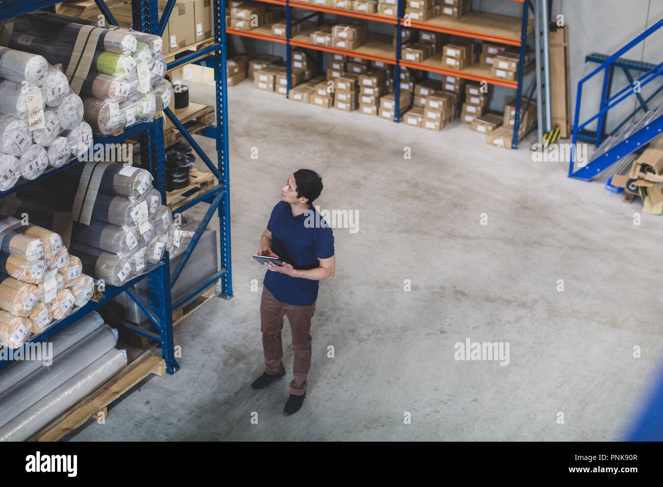 Colpo di overhead di lavoro maschio nel magazzino di distribuzione con tavoletta digitale Foto Stock