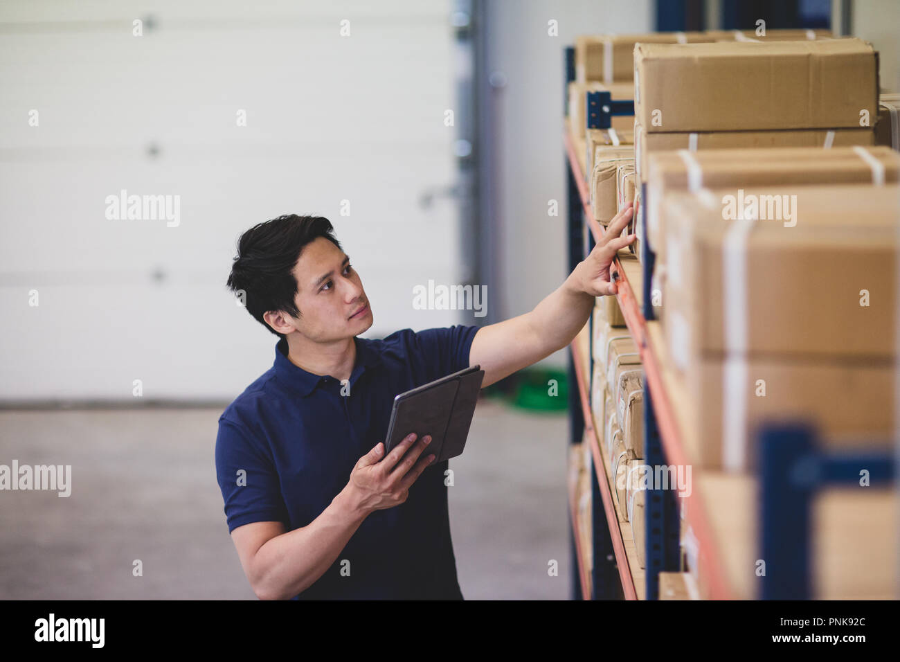 Lavoro maschio nel magazzino di distribuzione con tavoletta digitale Foto Stock