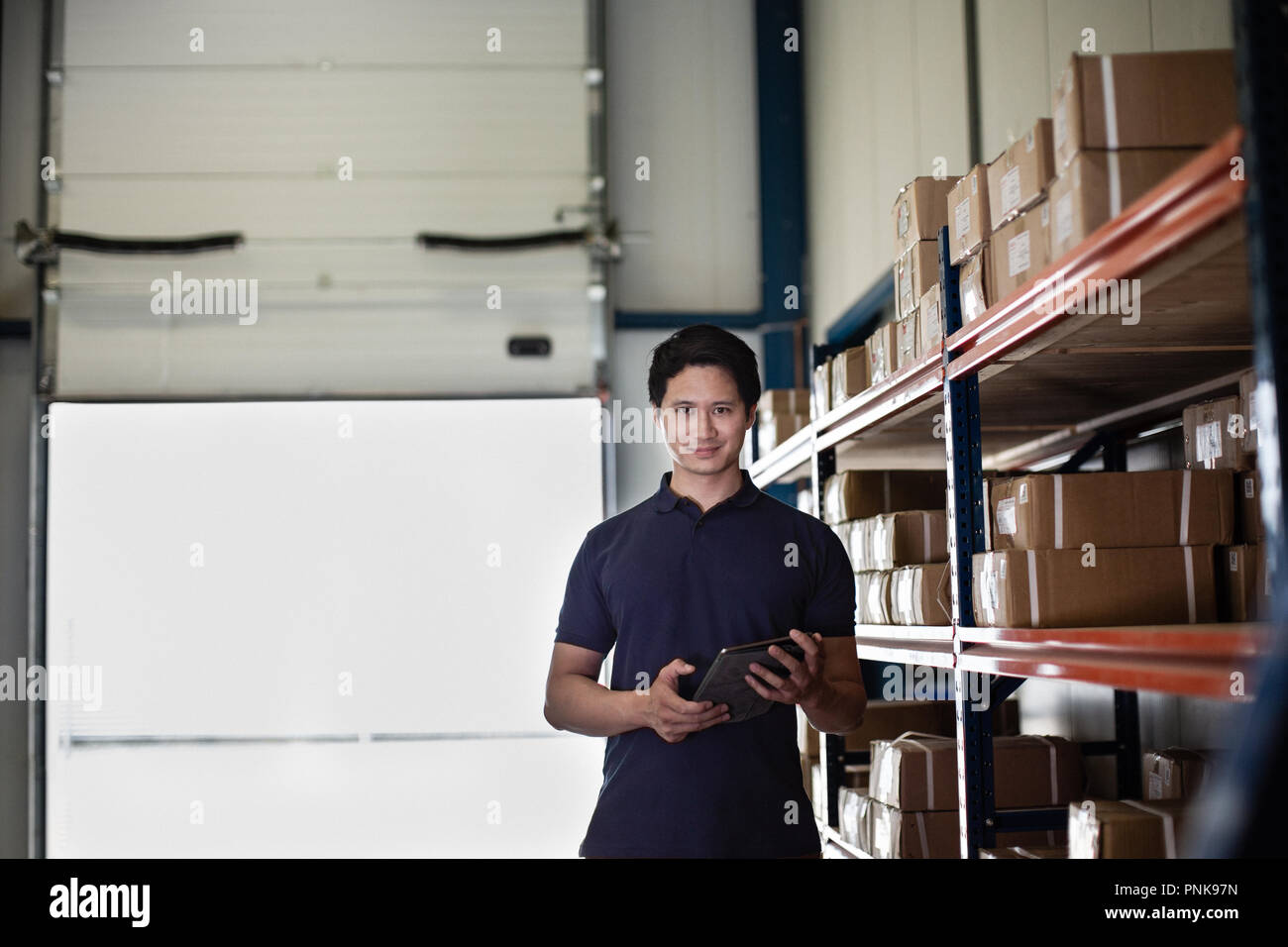 Ritratto di lavoro maschio nel magazzino di distribuzione con tavoletta digitale Foto Stock