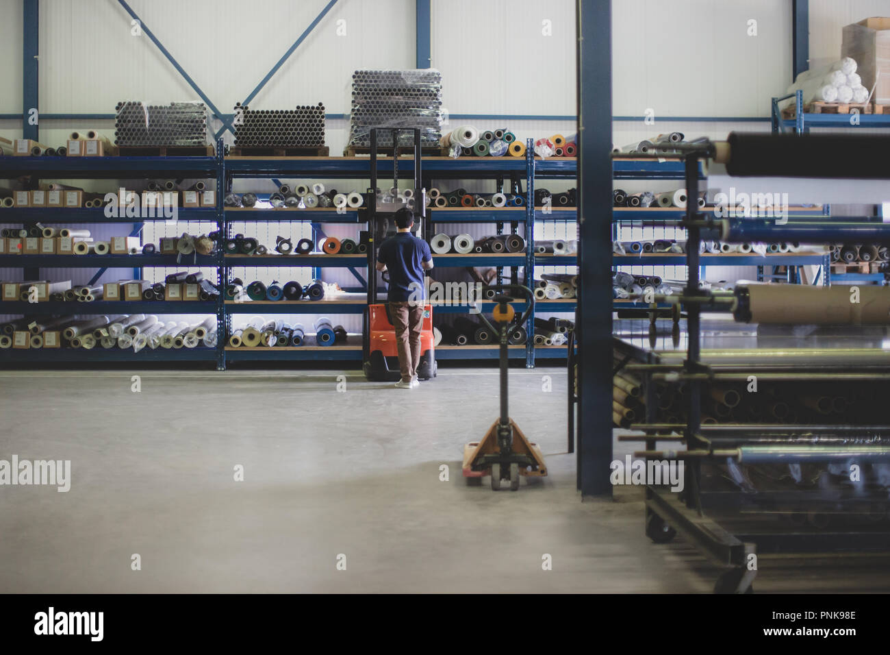 Lavoro maschile in magazzino utilizzando il carrello elevatore Foto Stock
