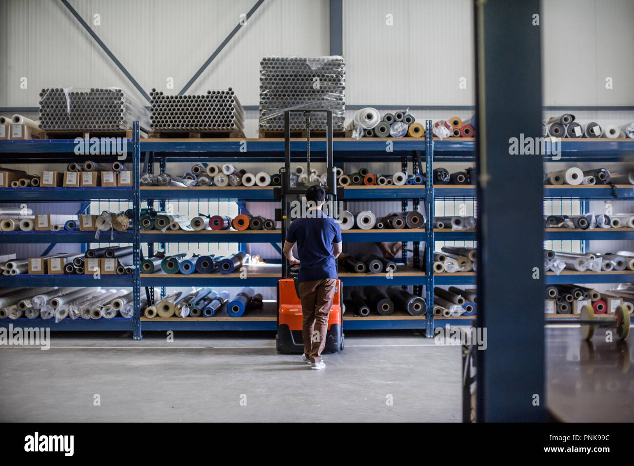 Lavoro maschile in magazzino utilizzando il carrello elevatore Foto Stock
