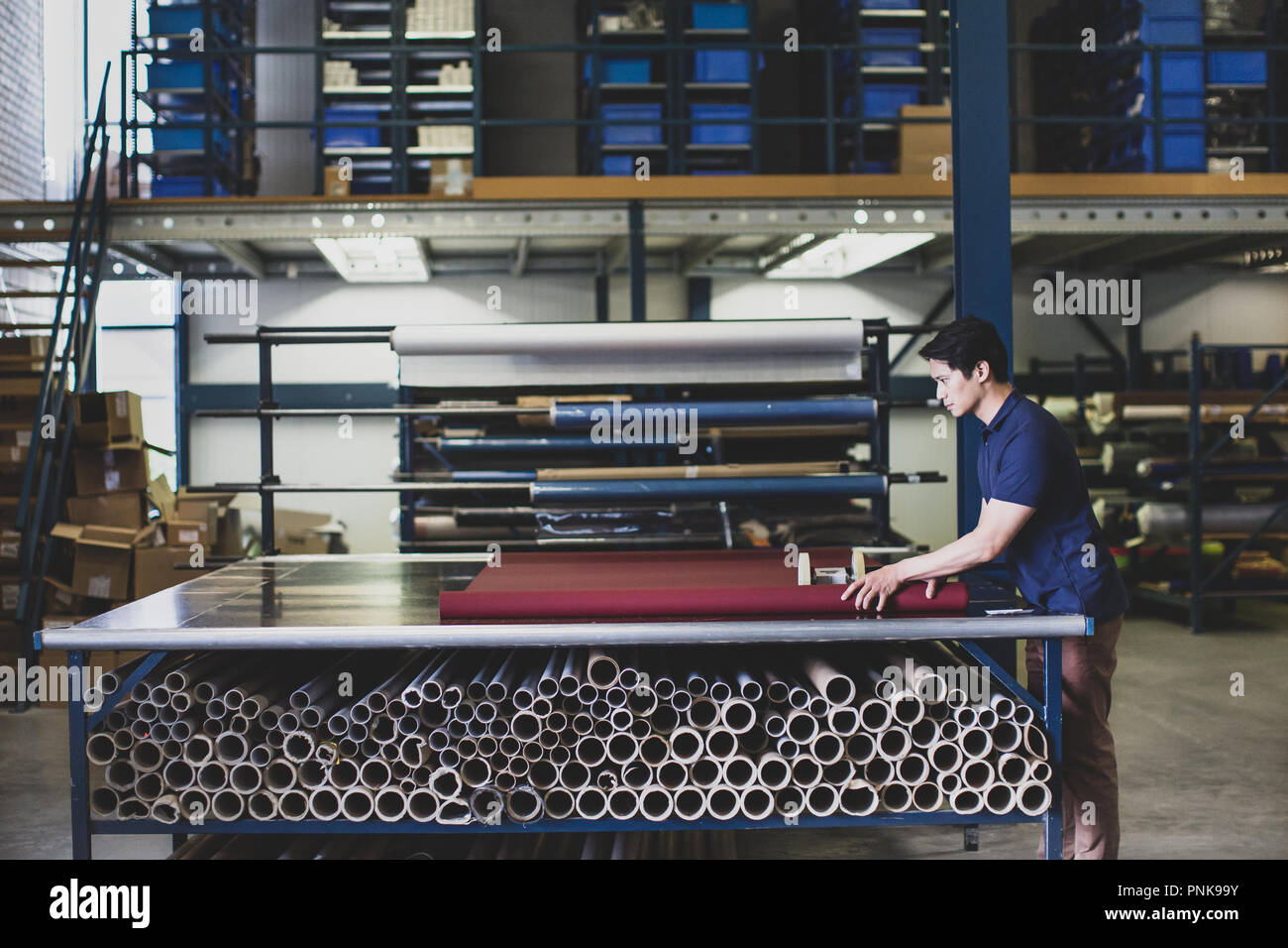 Maschio il taglio di tessuto in un magazzino di fabbricazione Foto Stock