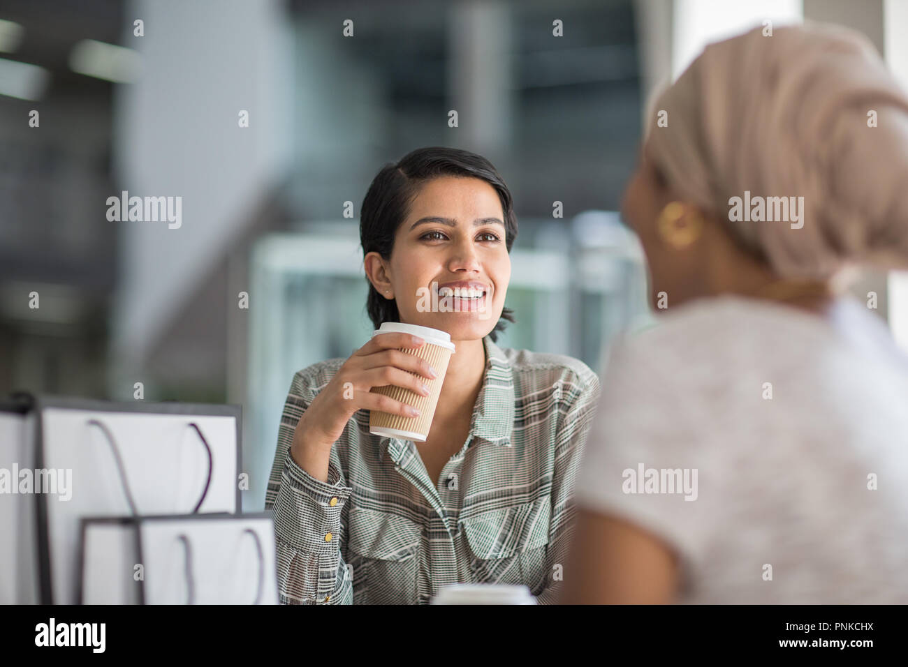 Femmina amici musulmani avente caffè insieme in un centro commerciale per lo shopping Foto Stock