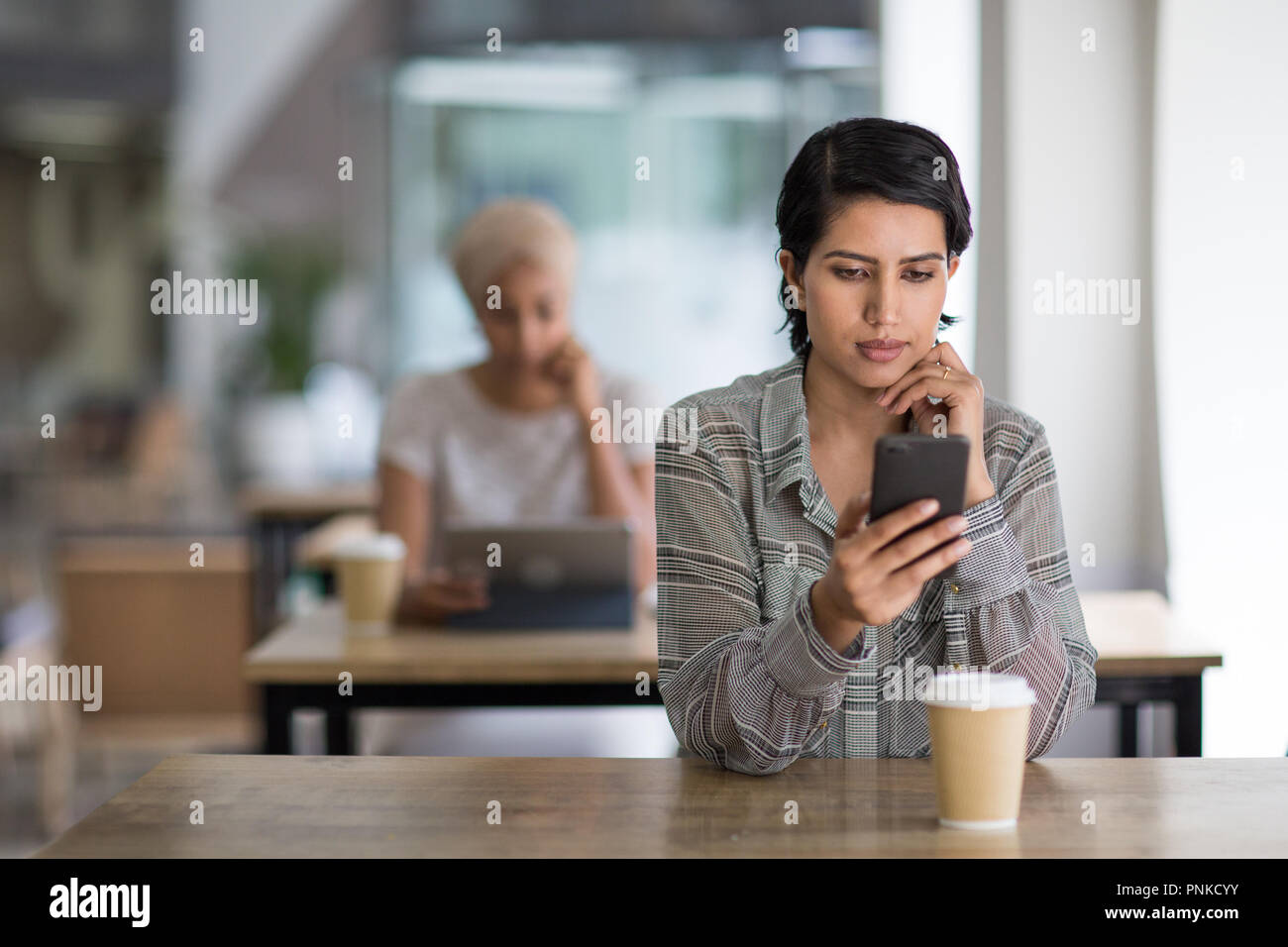 Femmina araba utilizzando uno smartphone in un cafe Foto Stock