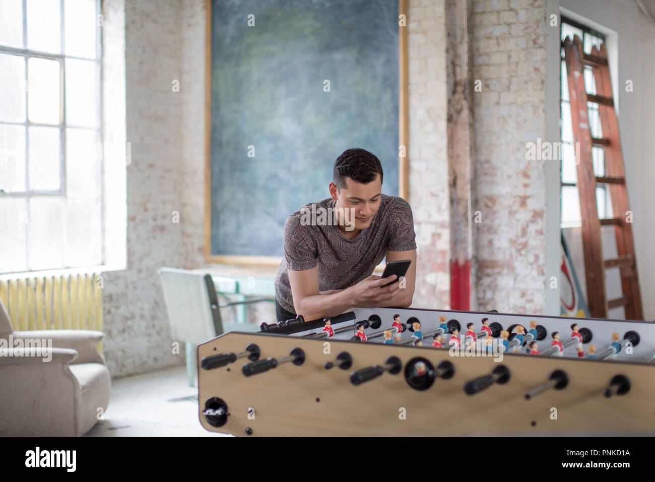 Giovani maschi adulti utilizza lo smartphone in un ufficio creativo Foto Stock