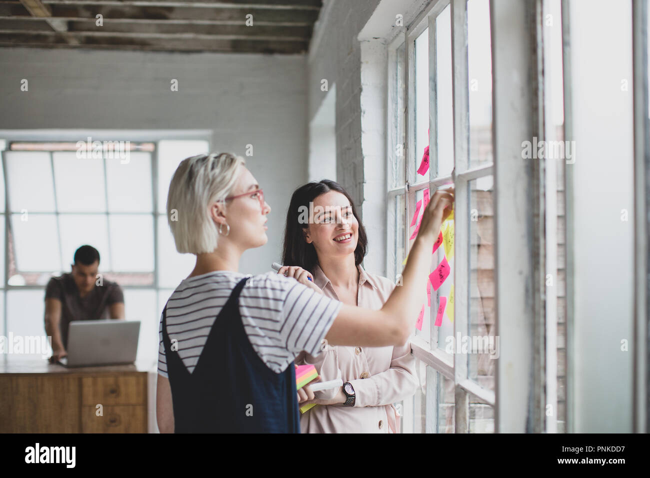 I giovani adulti il brainstorming in un ufficio creativo con note adesive Foto Stock