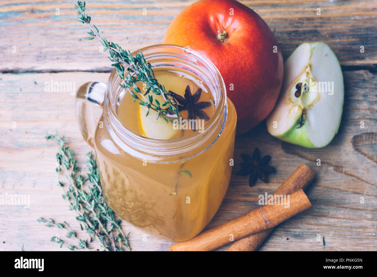 Sidro di mela (rimuginassero sidro di mela) o chai-der con bastoncini di cannella e mele fresche su sfondo di legno. Bevande d'autunno. L'inverno dell'umore. Foto Stock