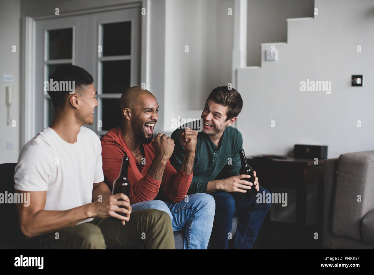 Amici maschi a guardare lo sport in TV Foto Stock