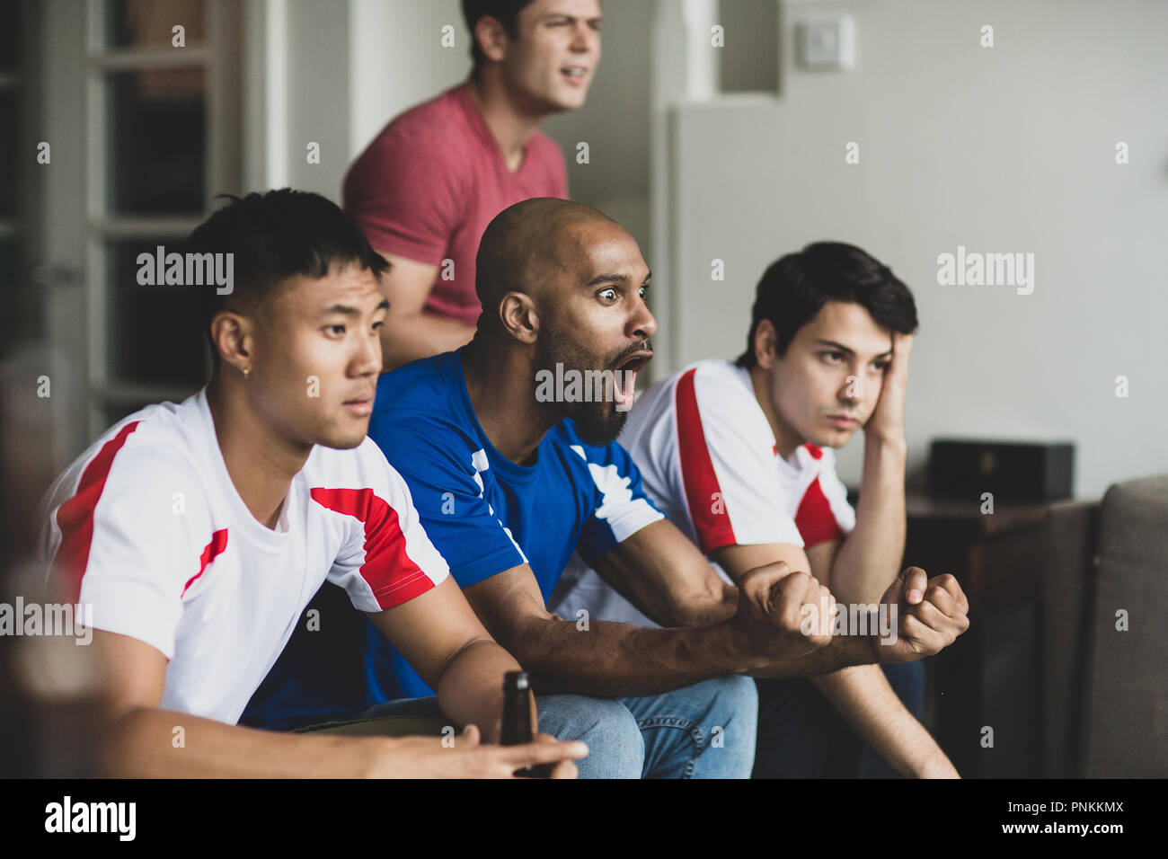 Gruppo di amici maschi a guardare una partita di calcio Foto Stock