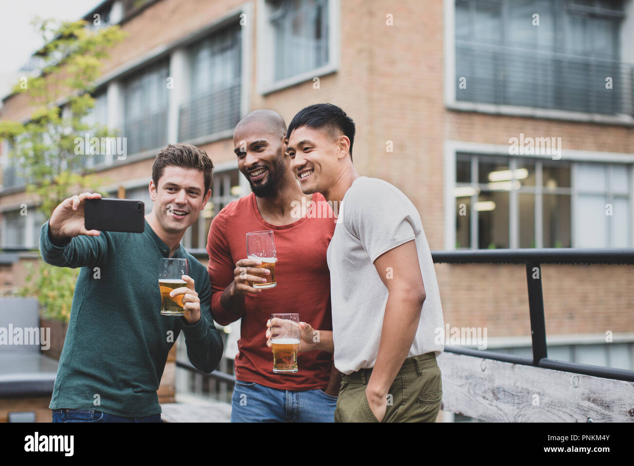 Gruppo di amici maschi prendendo un selfie in un bar esterno Foto Stock