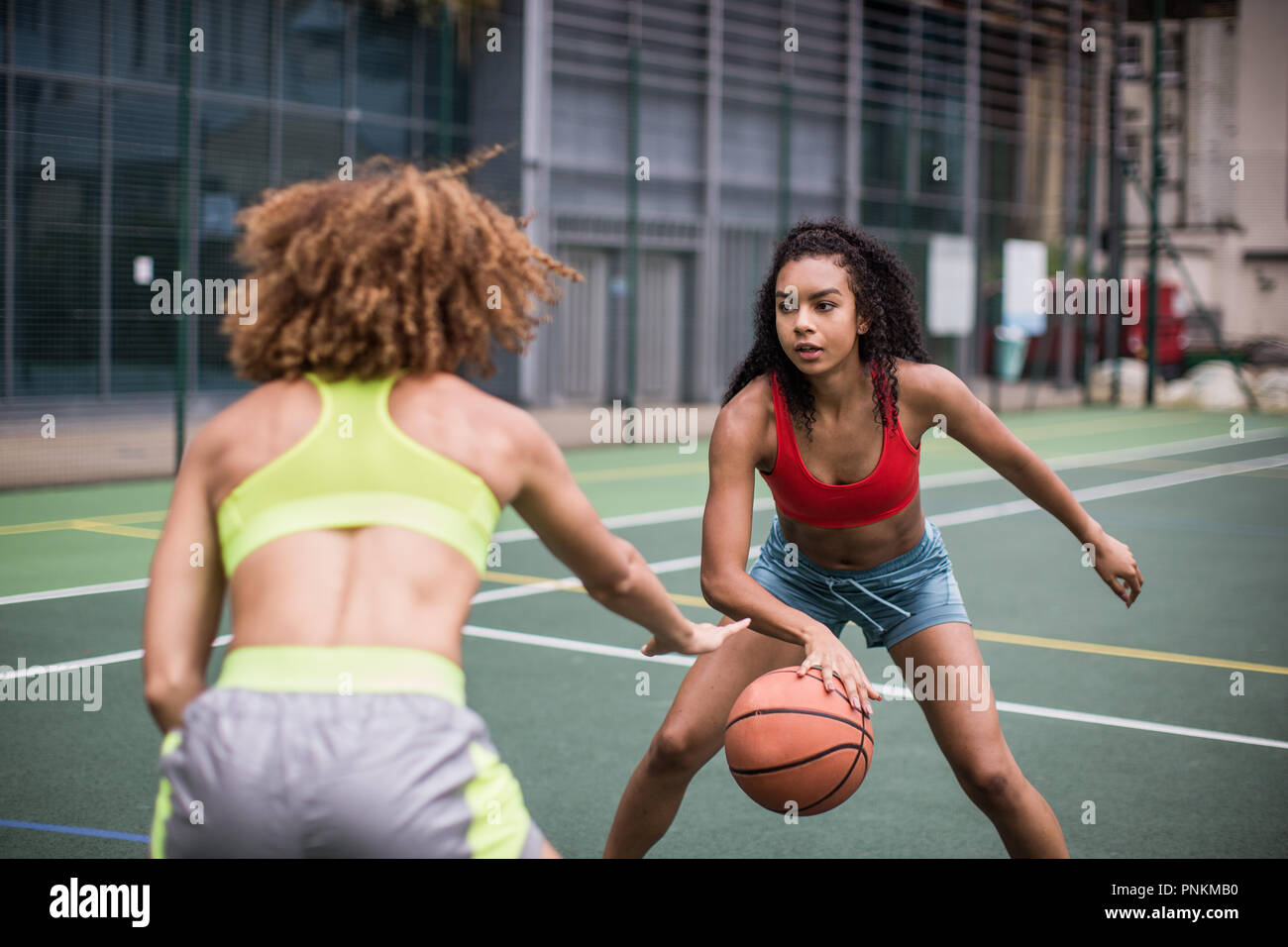 Giovani femmine adulte giocare a basket Foto Stock