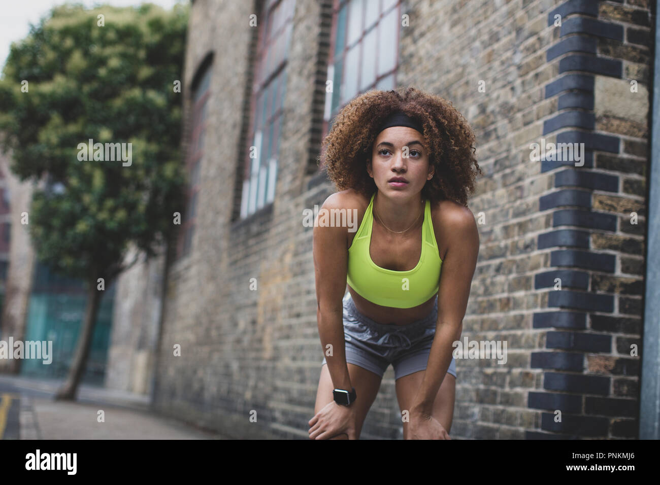 Giovane femmina adulta prendendo una pausa in una corsa in città urbana Foto Stock