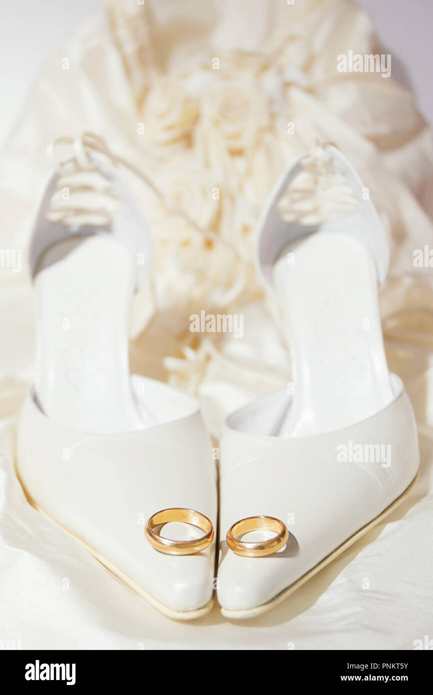 Gli anelli di nozze e scarpe da donna con un abito sullo sfondo Foto Stock