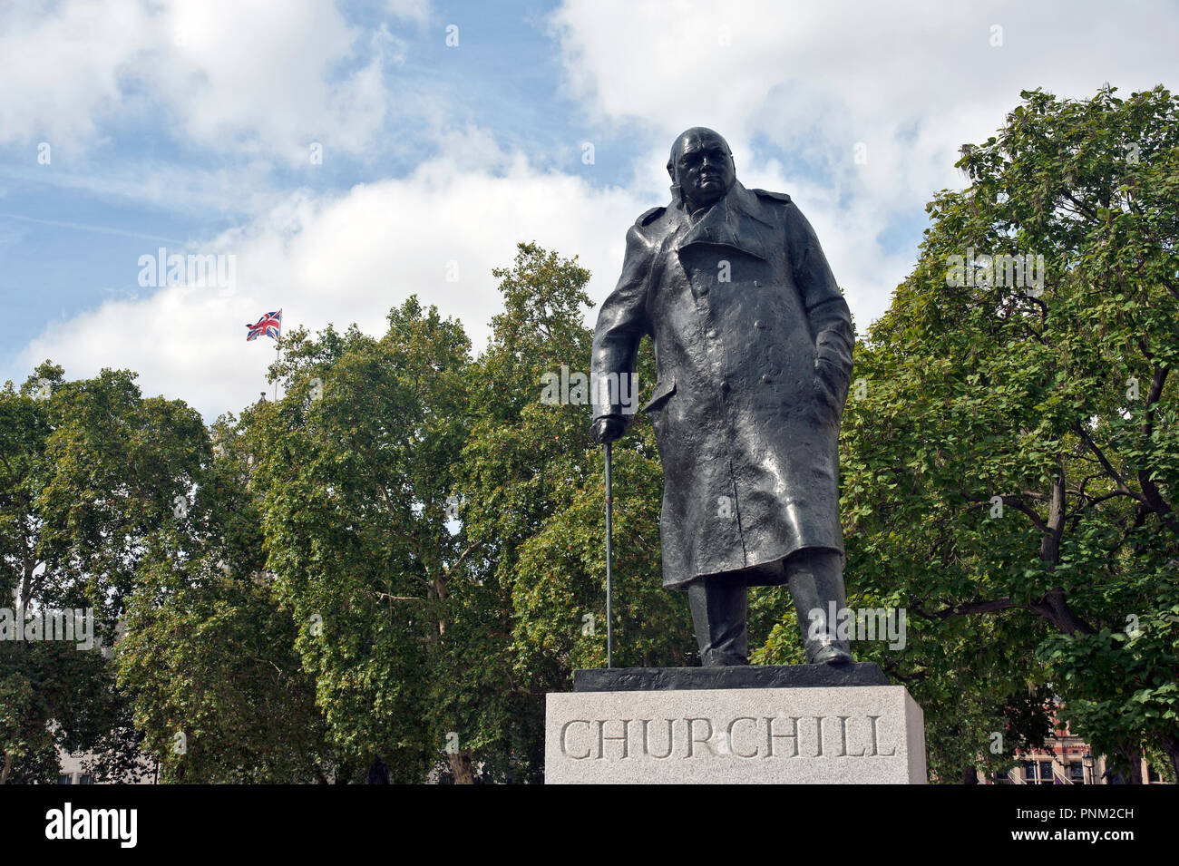 Statua di Sir Winston Churchill, la piazza del Parlamento, London, Regno Unito in primo piano con Unione Jack battenti in background. Foto Stock
