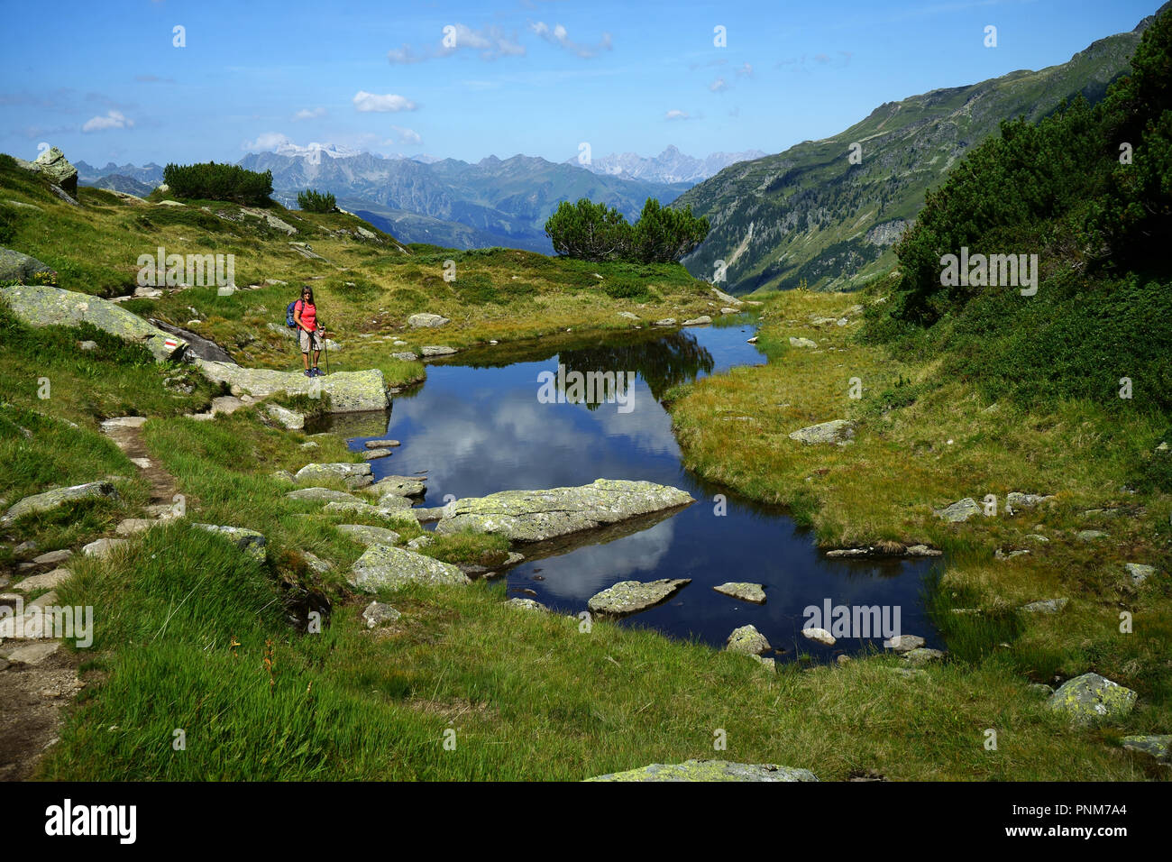 Escursionista sul piccolo lago sul sentiero per Breitspitze (3196m) girandola - Galtür, Paznaunvalley, Tirolo, Austria Foto Stock