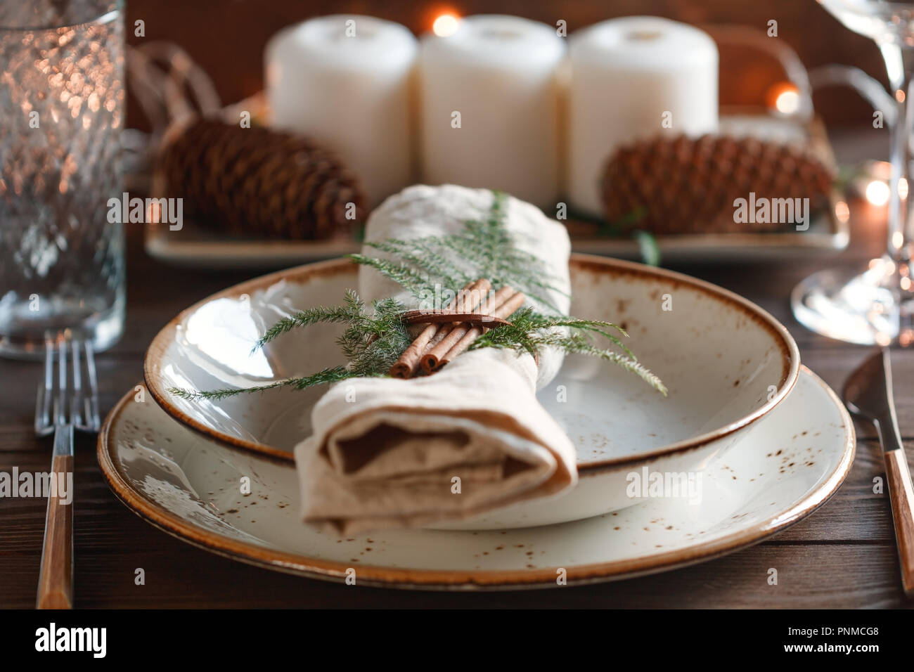 Decorate il ringraziamento impostazione tabella tra candele bianche e i coni. Il concetto di una cena di gala. Foto Stock