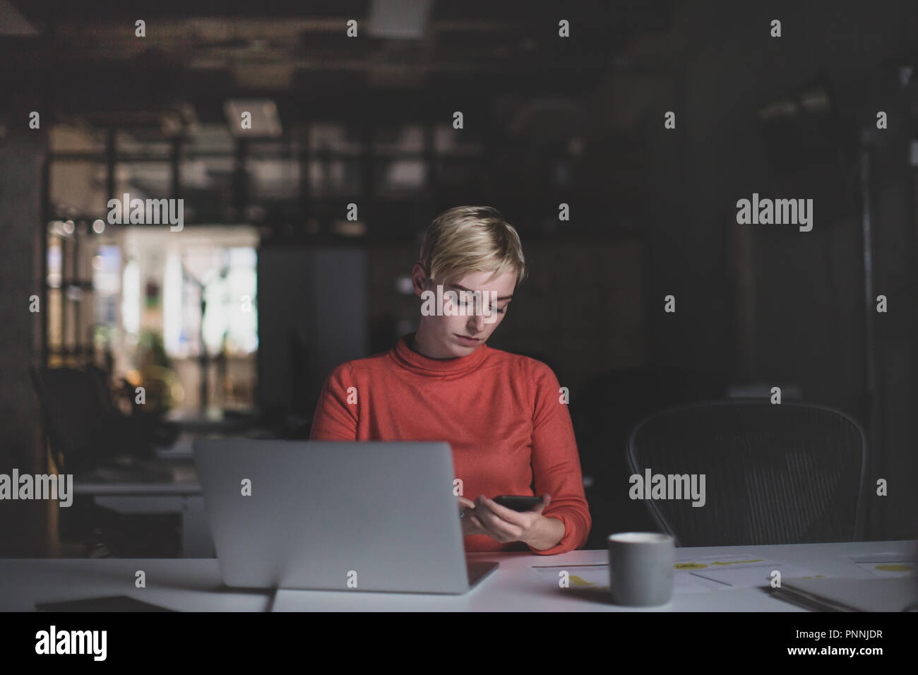 Giovane femmina adulta lavora fino a tardi in un ufficio Foto Stock