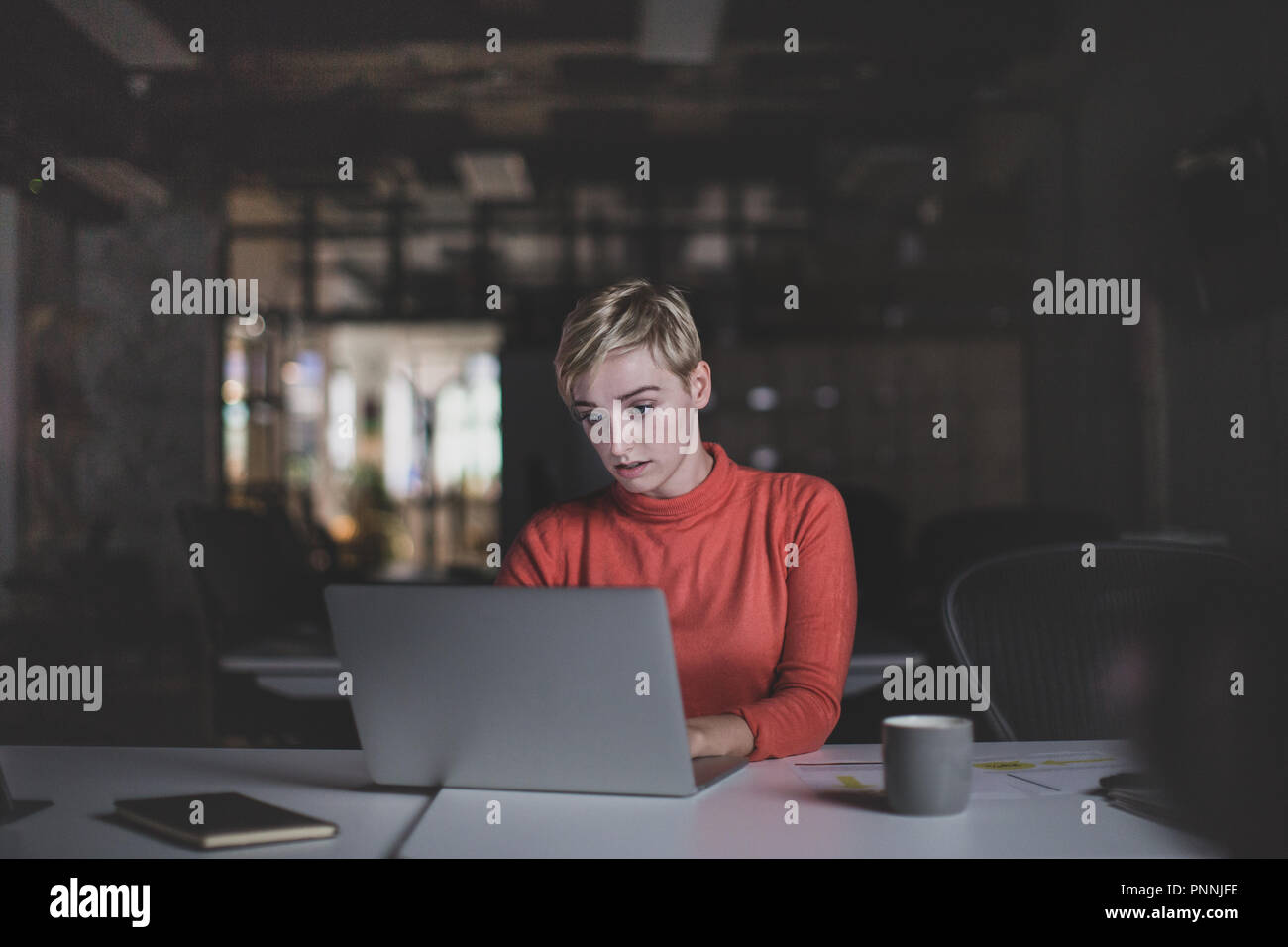 Giovane femmina adulta lavora fino a tardi in un ufficio Foto Stock