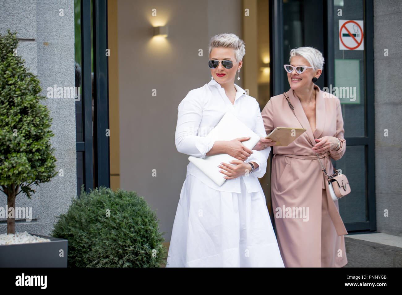 Due imprenditrice camminando sulla strada vicino edificio. business donna andare insieme con computer tablet Foto Stock