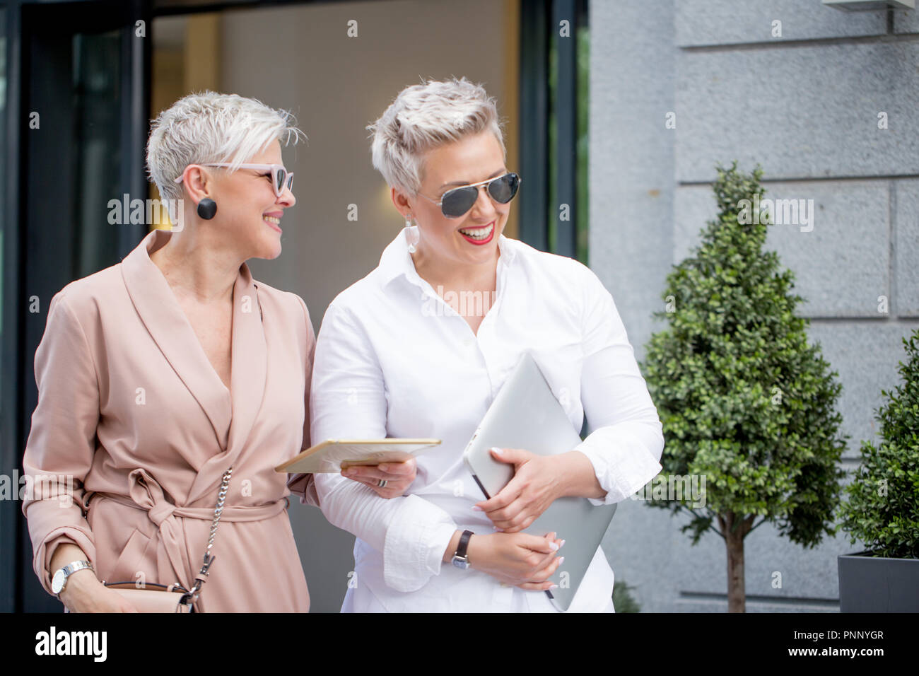 Due imprenditrice camminando sulla strada vicino edificio. business donna andare insieme con computer tablet Foto Stock
