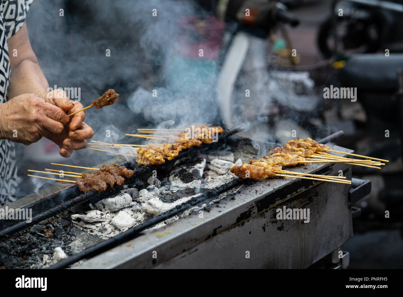 Hawker satay grill sulla sommità del fuoco di carbone di George Town, Penang. Un'attrazione turistica in Malesia per la sua popolare cucina di strada e patrimonio. Foto Stock