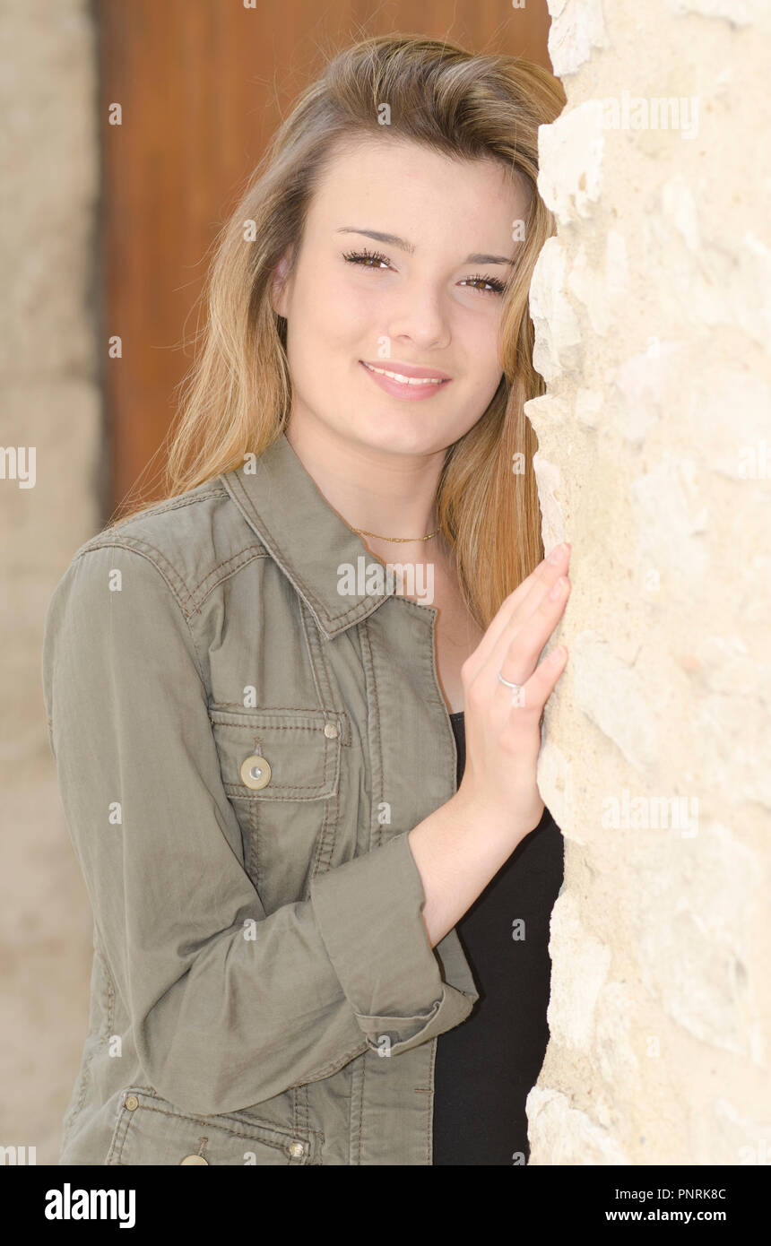 Bella ragazza sorridente contro un muro di pietra Foto Stock