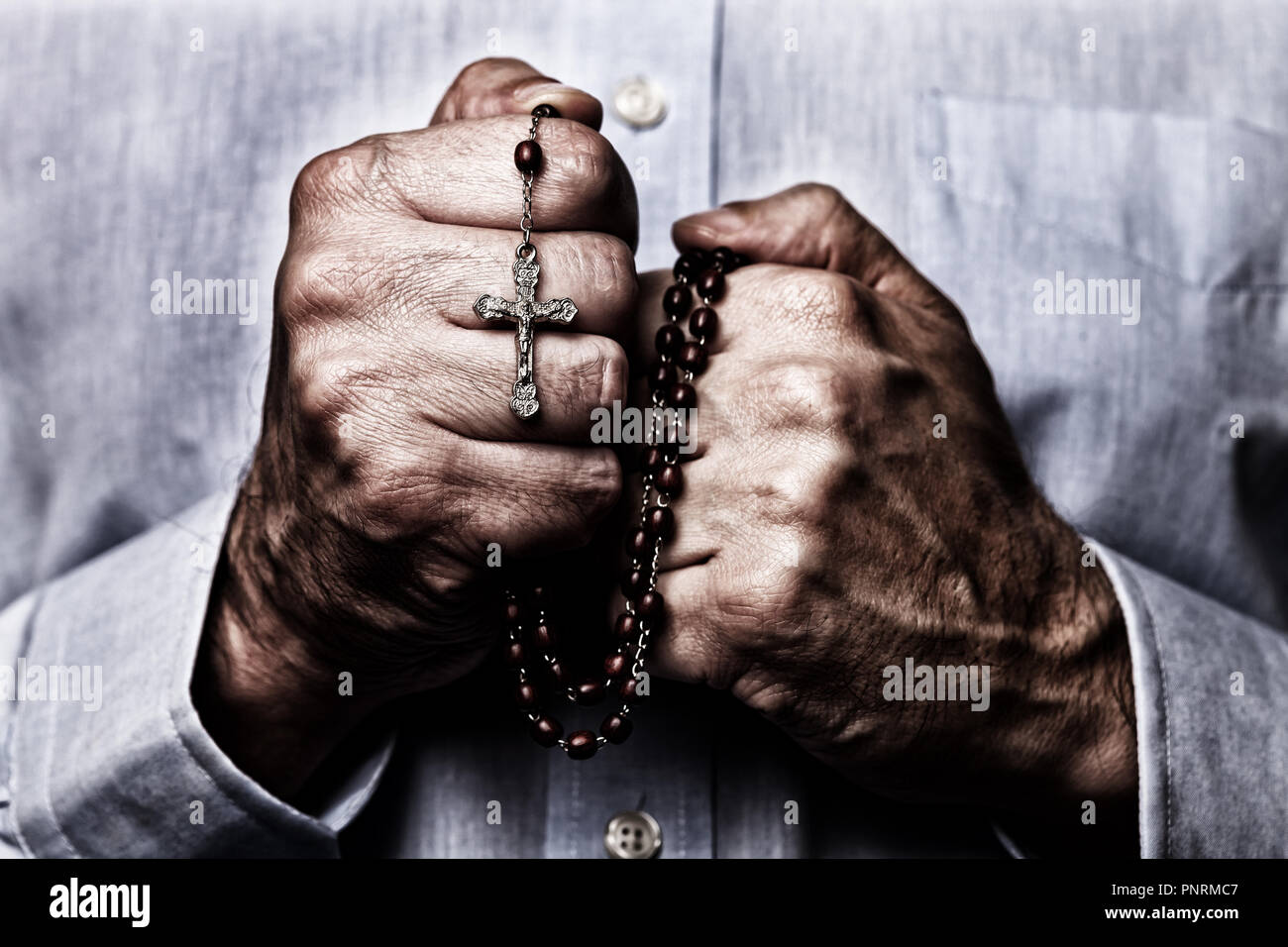 Americano africano mani maschio pregando tenendo un rosario perline con Gesù Cristo in croce o Crocifisso su sfondo nero. Coppia afro-americano wi Foto Stock