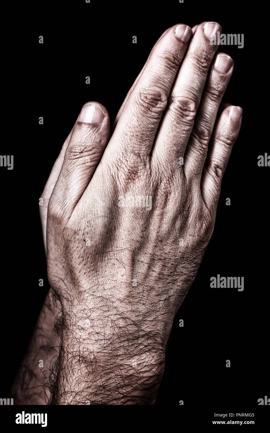 Mani maschio pregando con palme insieme. Sfondo nero. Close up man mano. Concetto di preghiera, di pregare, di fede e di religione, religiosi, di culto Foto Stock